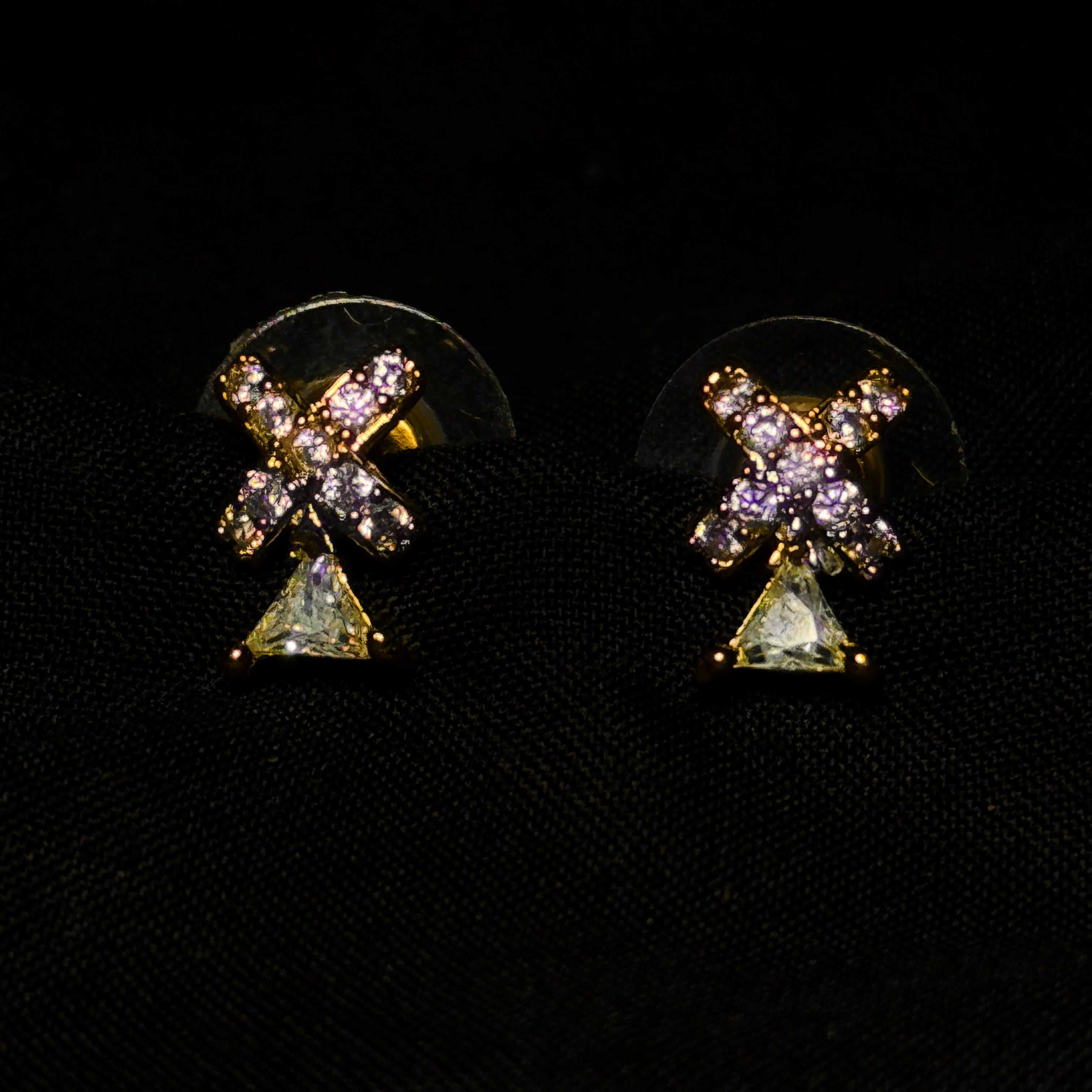 Pair of earrings with star and triangle design on a black background