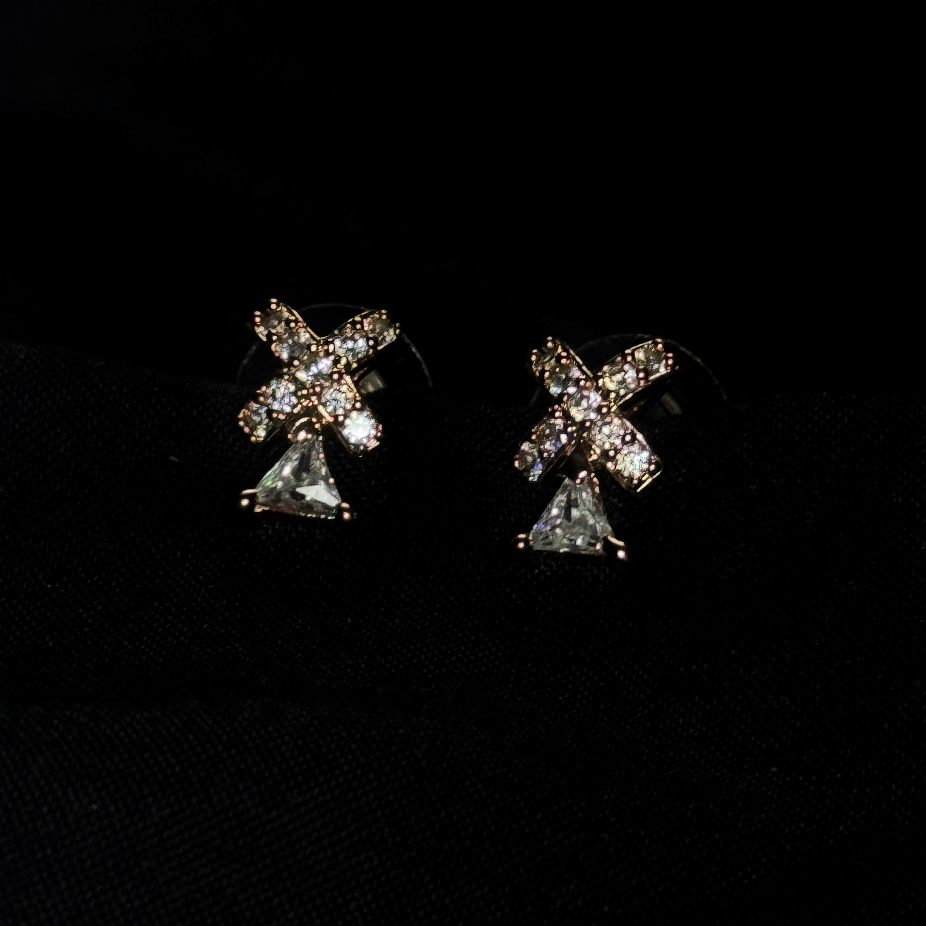 Pair of diamond cross earrings on a black background