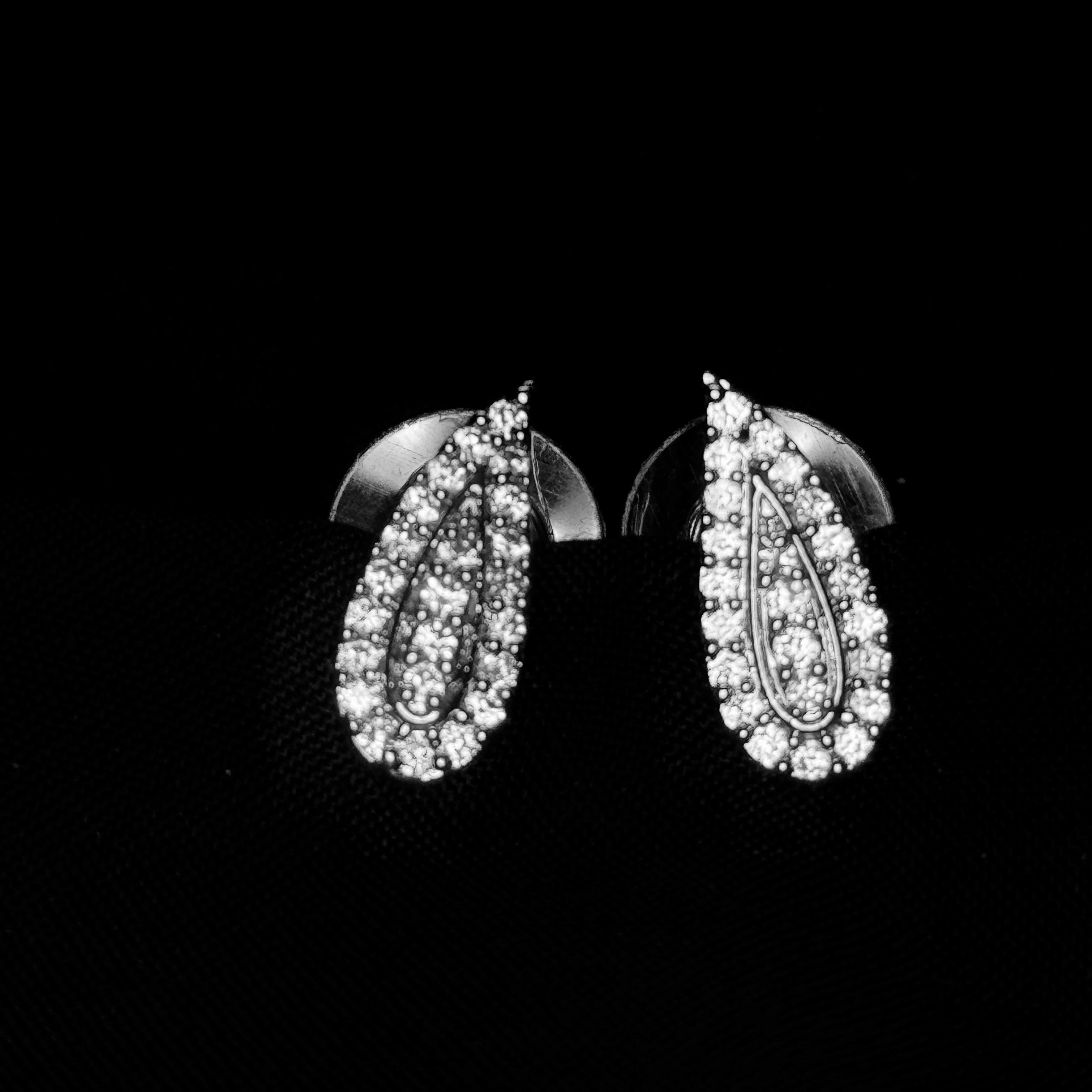 Pair of silver earrings with clear stones on a black background