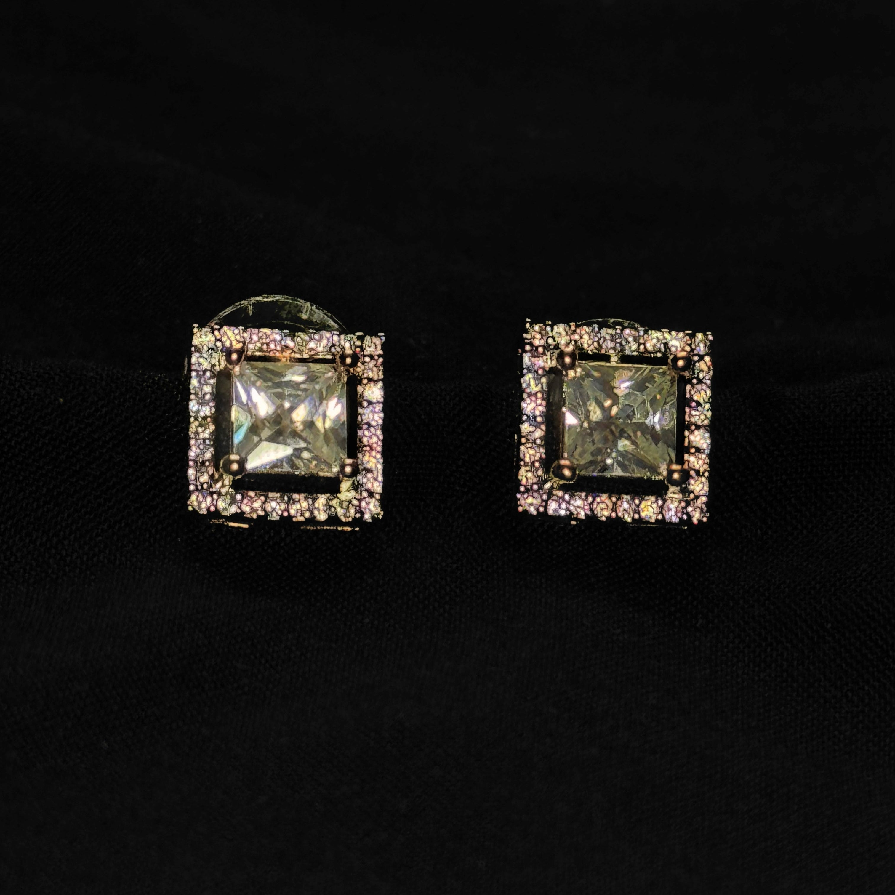 Square-shaped earrings with gemstones on a black background