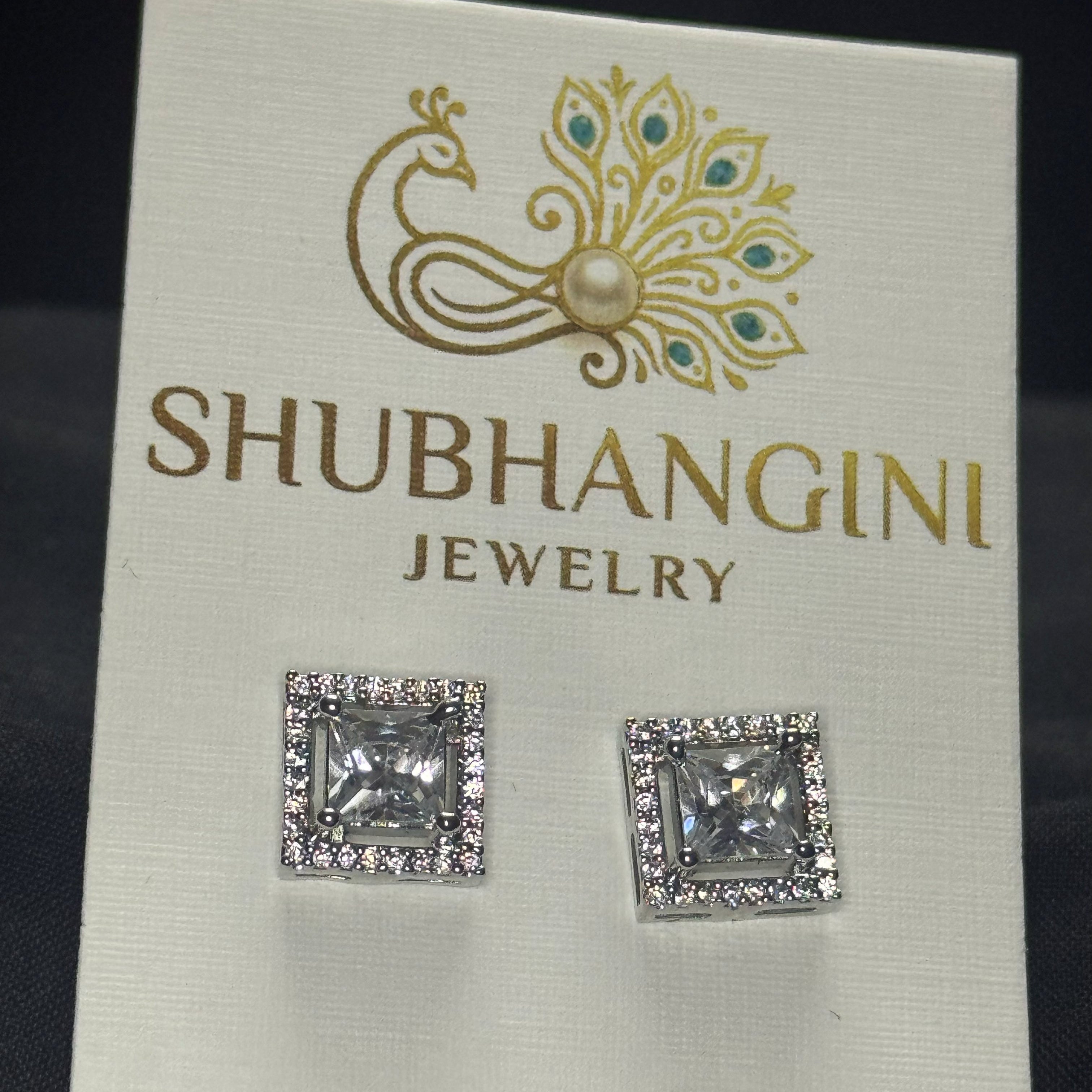 Square crystal earrings on a Shubhangini Jewelry card against a dark background