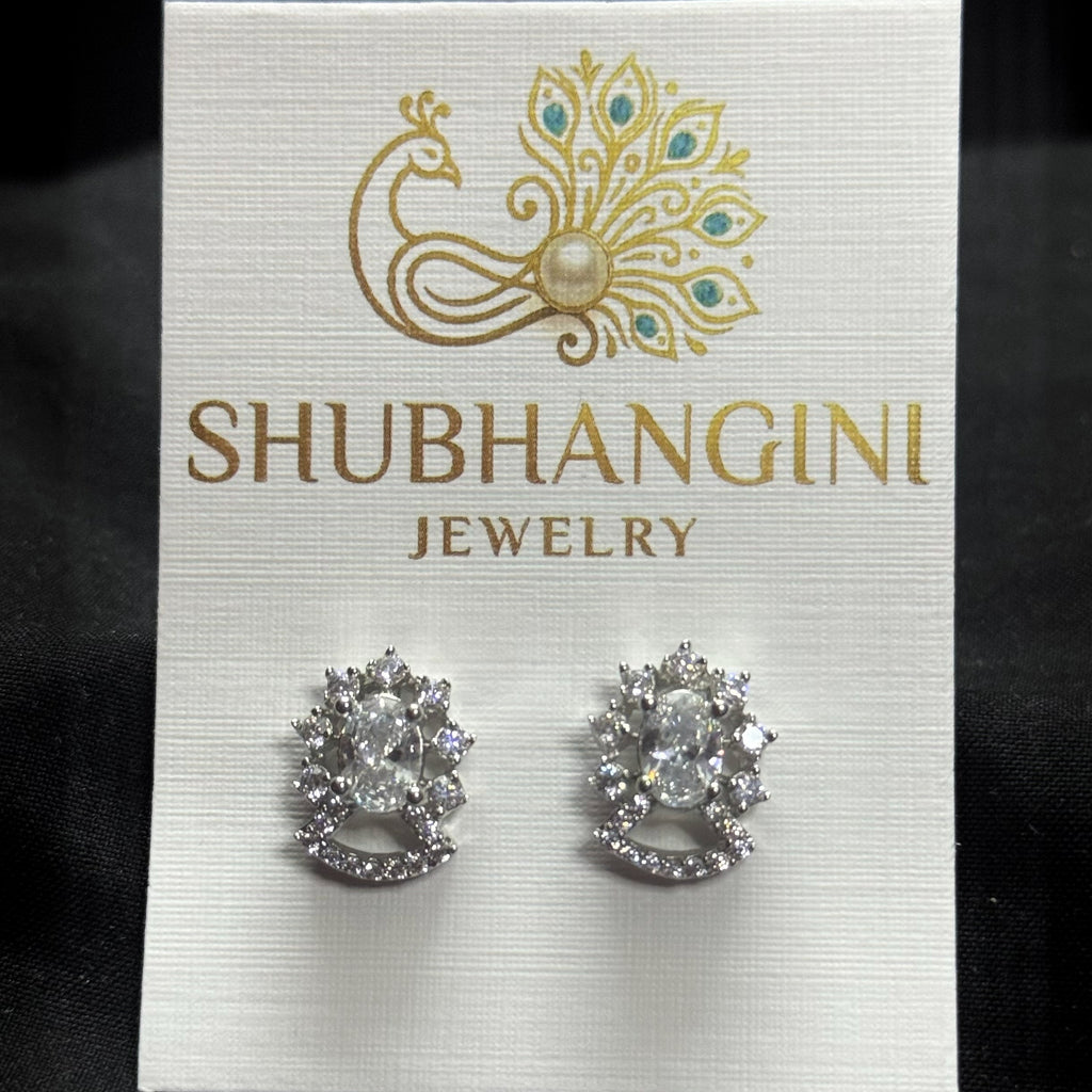 Pair of silver earrings on a Shubhangini Jewelry card against a black background