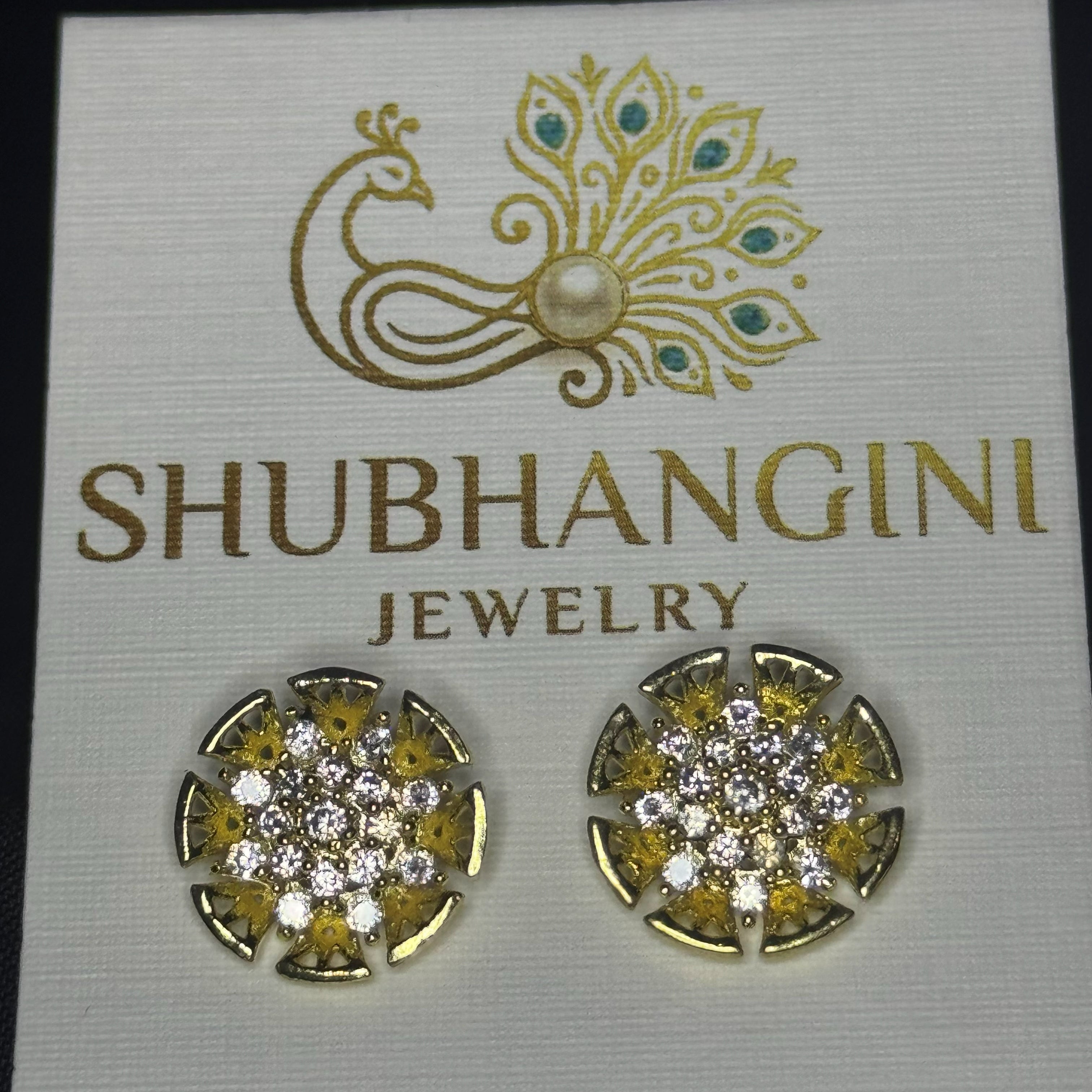 Gold and diamond earrings on a Shubhangini Jewelry card.