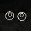 Pair of spiral-shaped earrings with rhinestones on a black fabric background