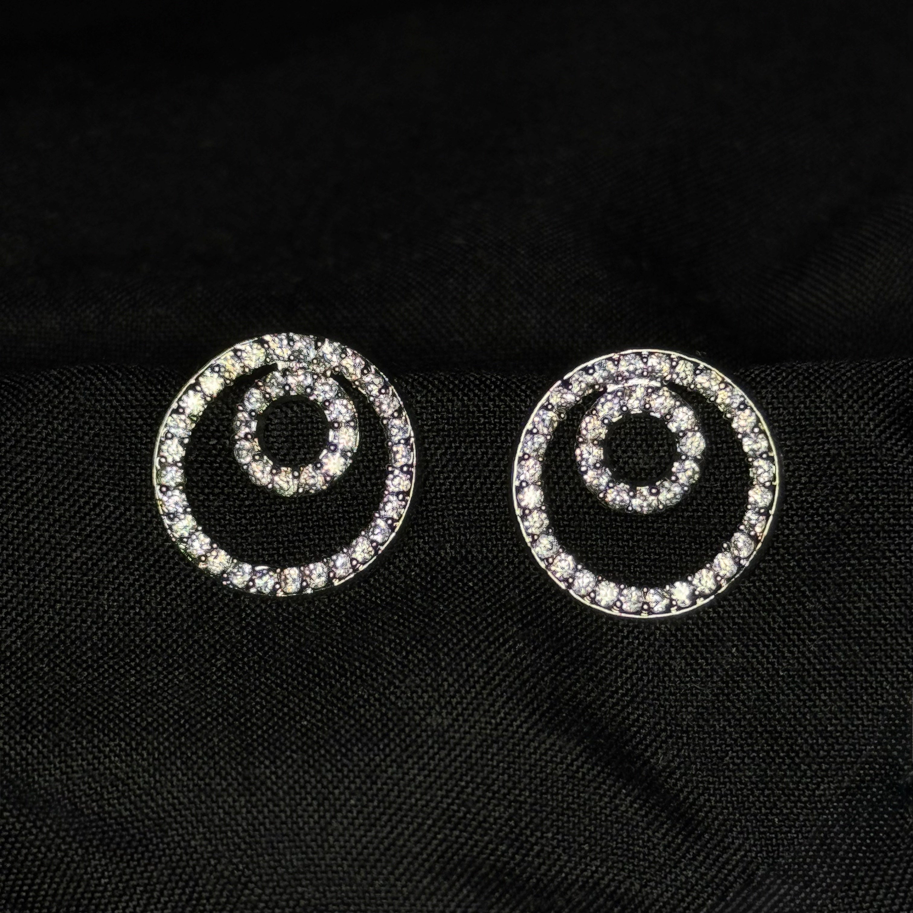 Pair of spiral-shaped earrings with rhinestones on a black fabric background