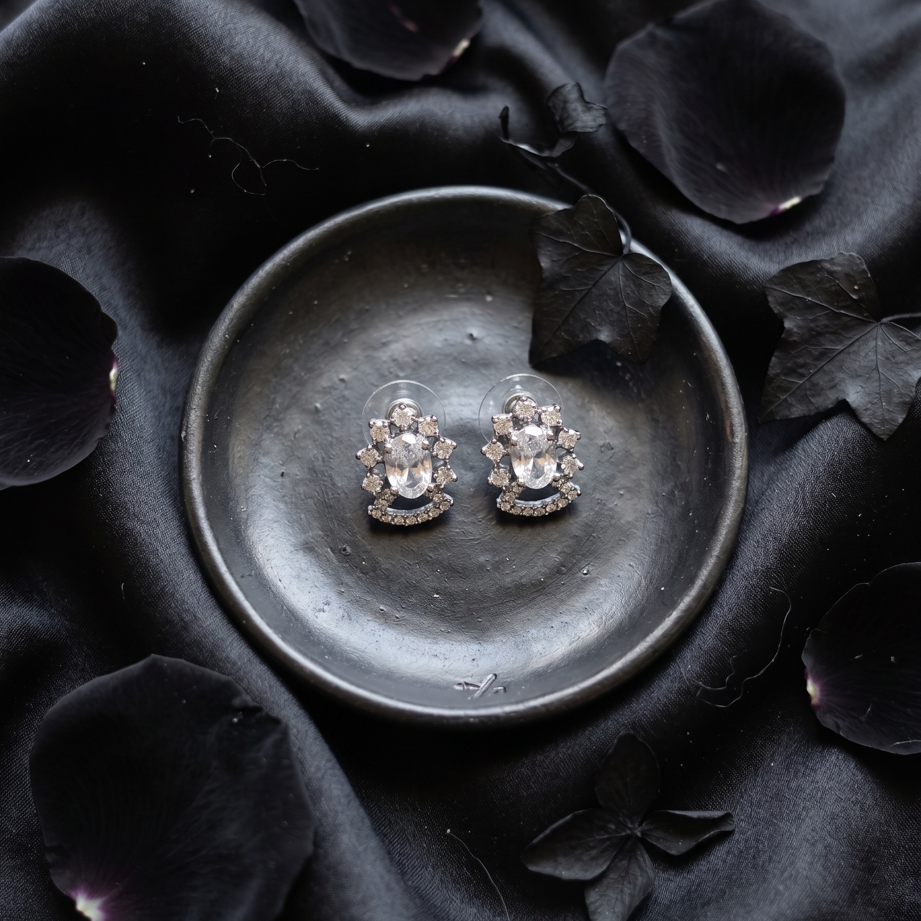 Pair of floral earrings on a dark dish with black petal background