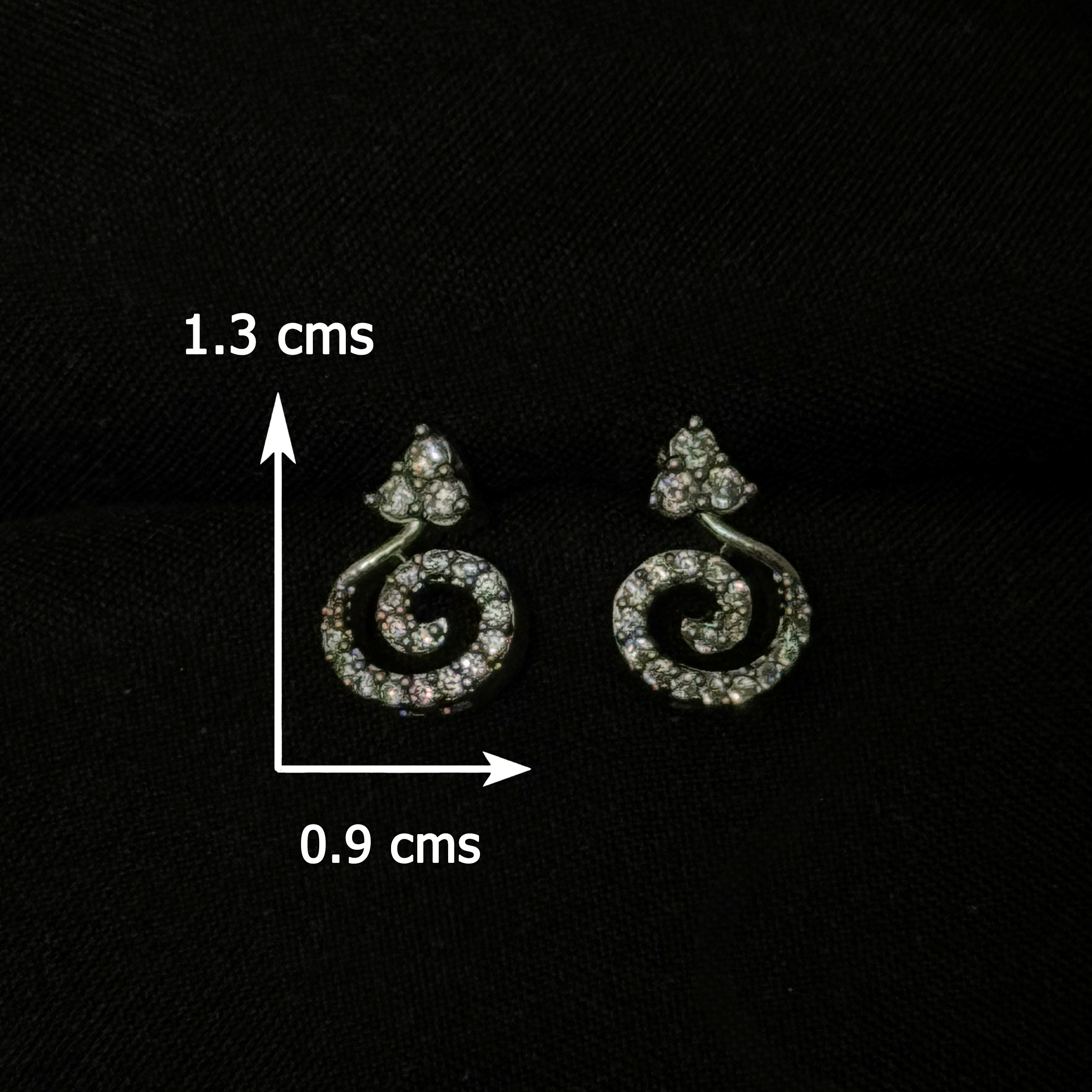Pair of silver earrings with measurement details on a black background