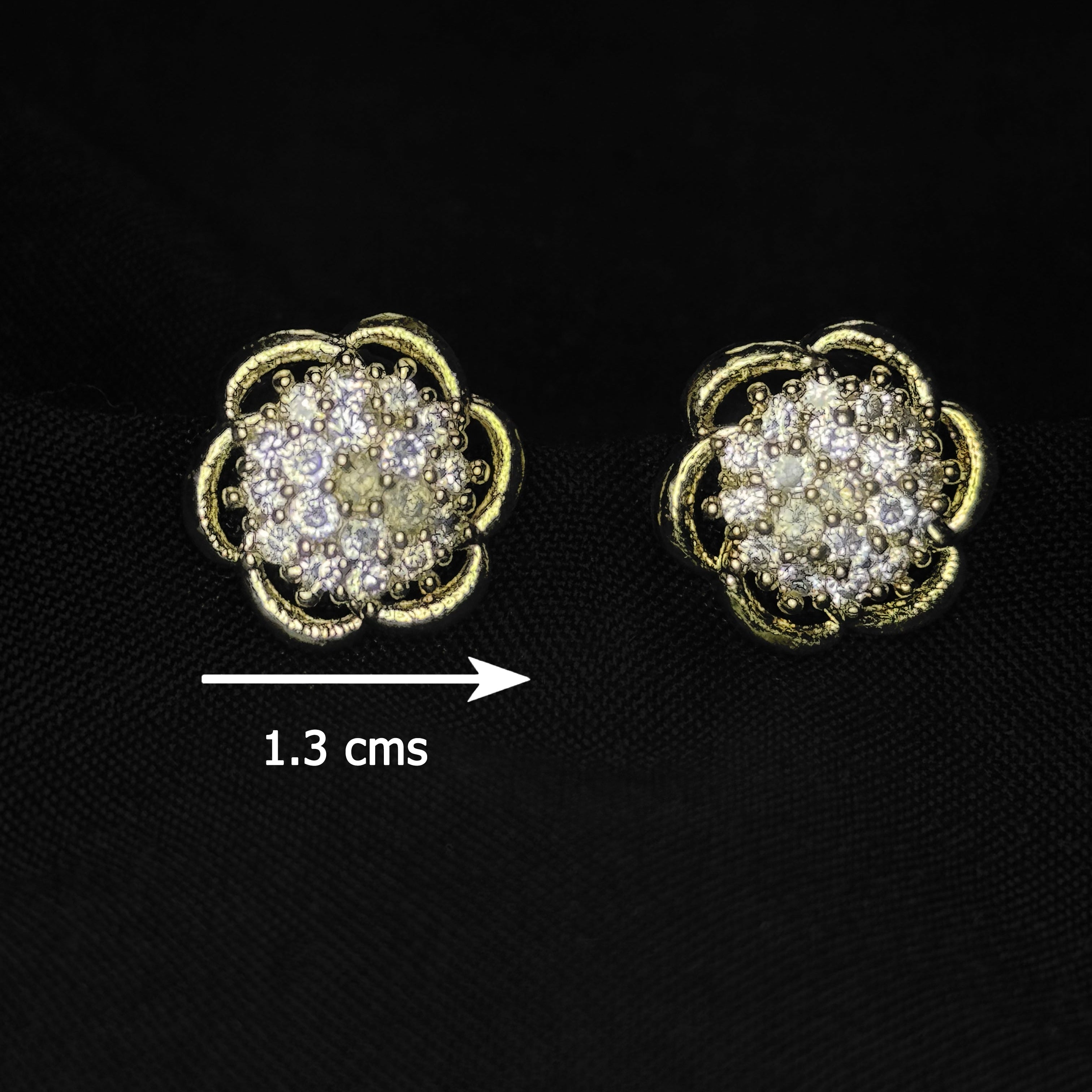 Pair of gold and diamond earrings on a black background with measurement label.