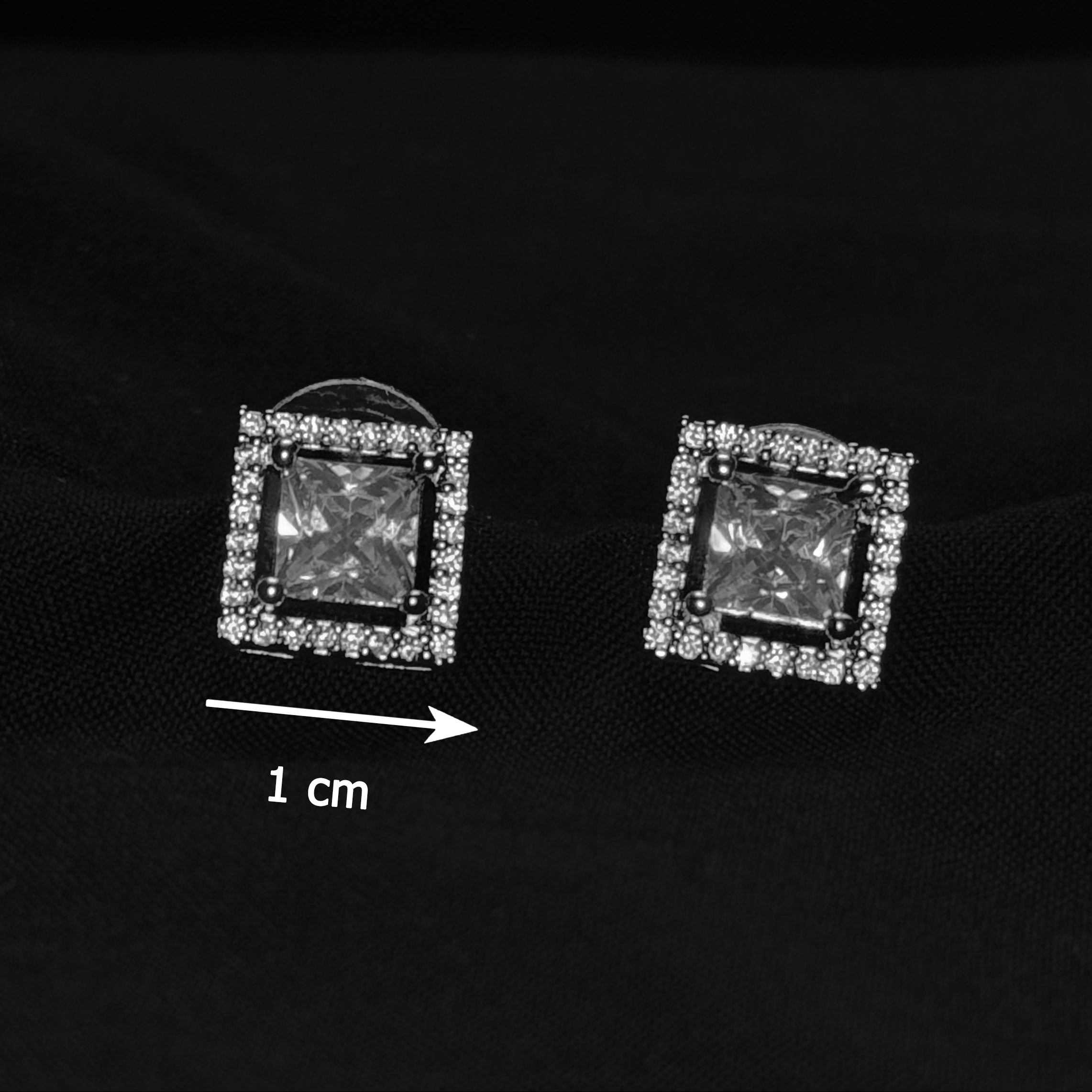 Pair of square-shaped earrings with clear stones on a black background